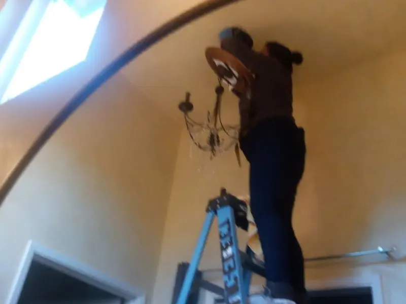 Electrician installing a chandelier in a Walbridge residence